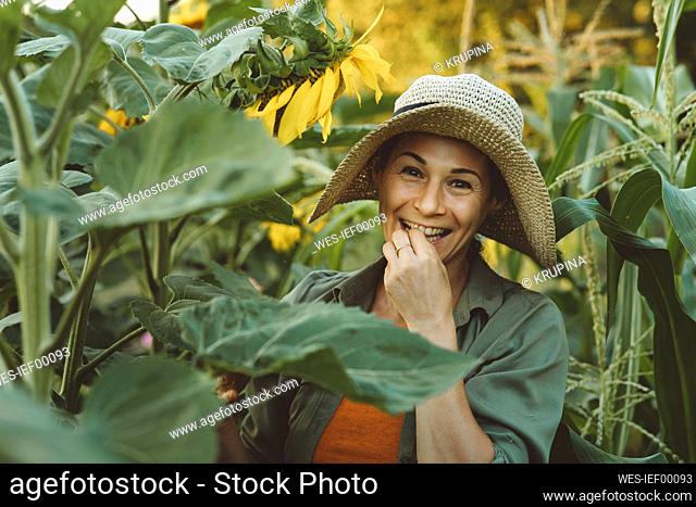 Smiling mature woman eating sunflower seed in garden
