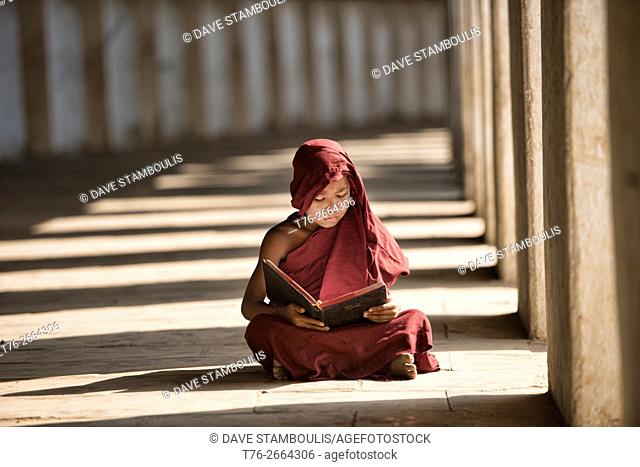 A young monk reading in the entrance to Shwezagon Pagoda, in Bagan, Myanmar