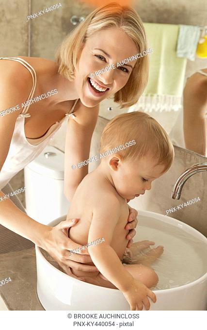 Woman giving bath to her baby in a wash bowl