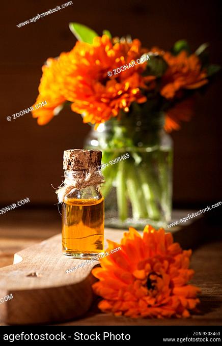 Essential oil made from marigold on rustic wooden background