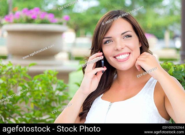 Attractive Young Adult Female Talking on Cell Phone Outdoors on Bench