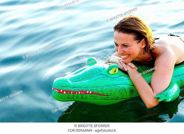 Woman in sea with inflatable crocodile