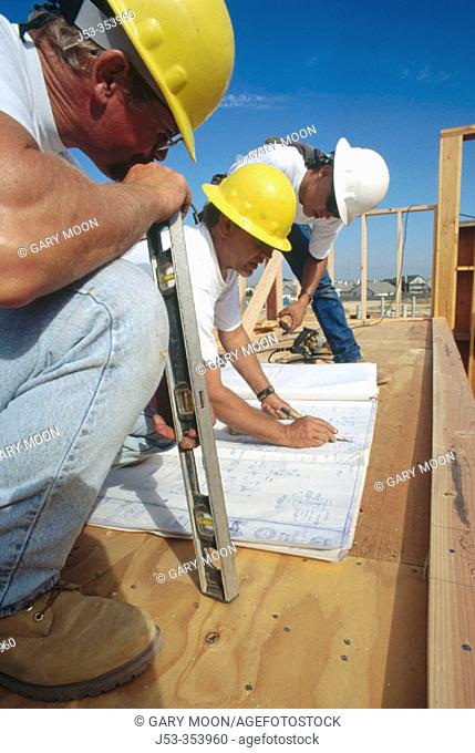 Jobsite foreman giving instructions to carpenters on school construction job, California, USA