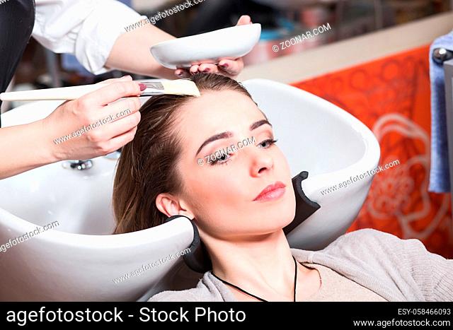 Barber girl combing her hair in beauty saloon. Beautiful lady having her hair washed by hairdresser in hairdressing saloon