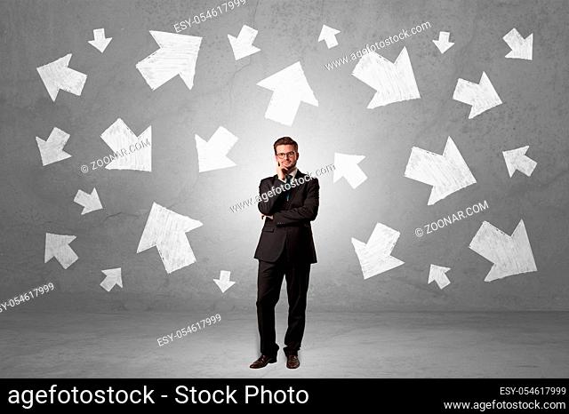 Handsome businessman standing in front of a wall with chalk drawn arrows