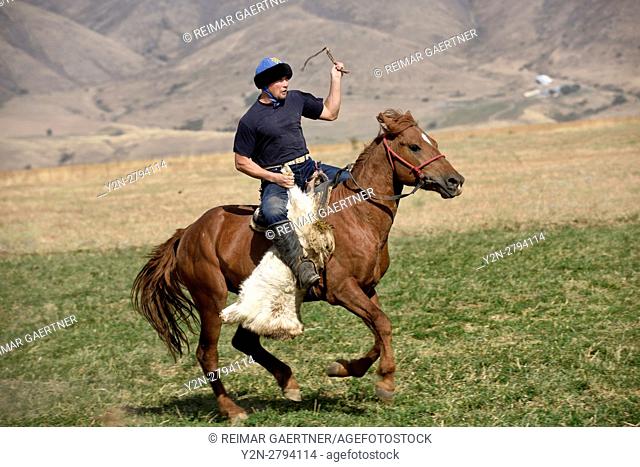 Kazakh man carrying goat carcass on horseback in Kokpar Tudabarai game near Aksu-Zhabagly Nature Reserve
