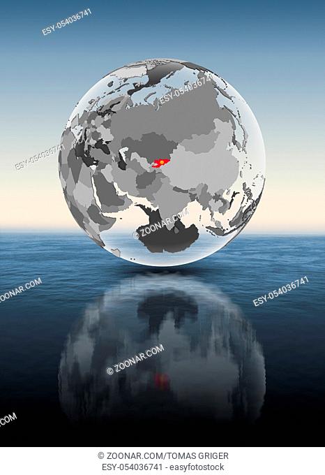 Kyrgyzstan with flag on translucent globe above water. 3D illustration