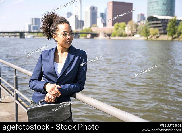 Thoughtful businesswoman with suitcase looking at River Main