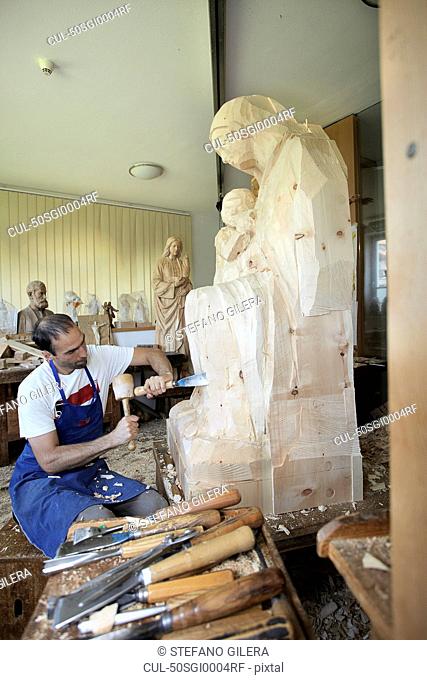Sculptor chiseling figure from wood