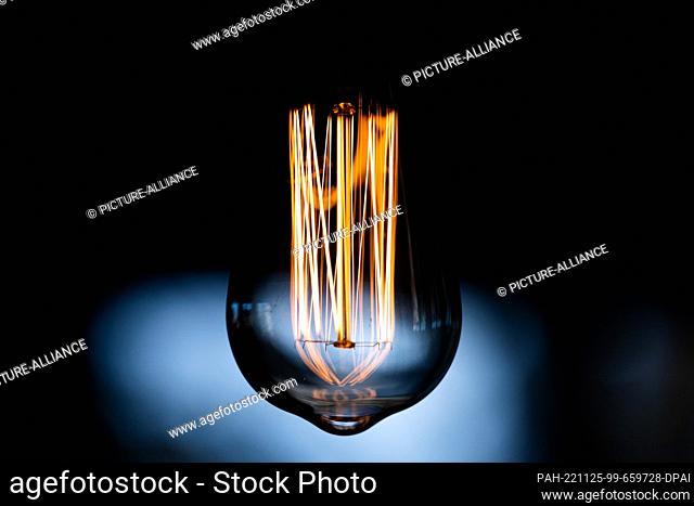 PRODUCTION - 25 November 2022, North Rhine-Westphalia, Cologne: ILLUSTRATION - A lamp lights up in a living room. Many electricity suppliers raise prices