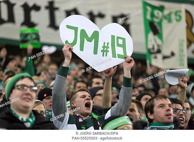 A fan of VfL Wolfsburg's holds a sign in his hands which reads 'JM 19' in reference to Wolfsburg's player Junior Malanda who recently died in a car accident...