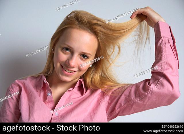 Portrait of a Beautiful Smiling Blonde Girl Pulling her Hair