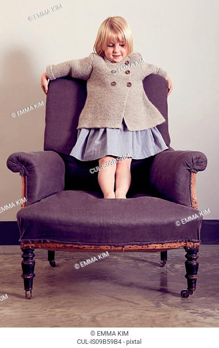 Girl standing on vintage armchair