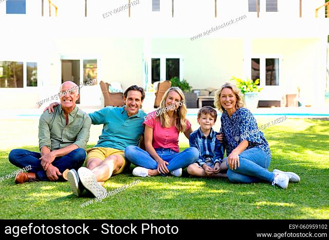Portrait of caucasian three generation family smiling while sitting together in the garden