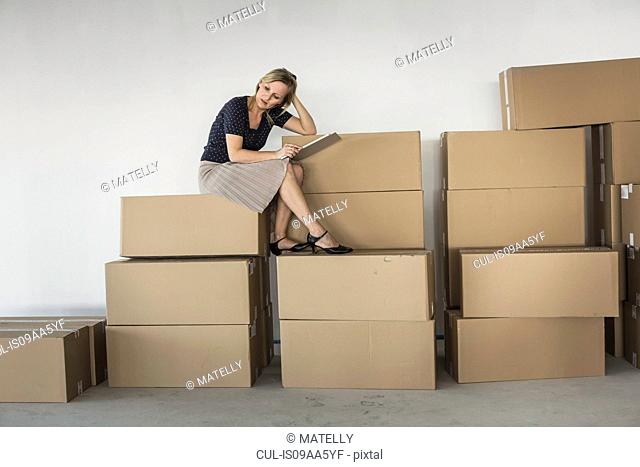 Businesswoman sitting on stack of cardboard boxes
