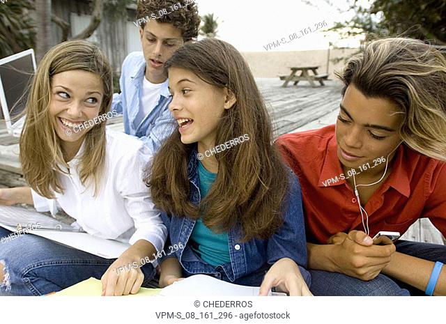 Close-up of two teenage girls sitting with two teenage boys