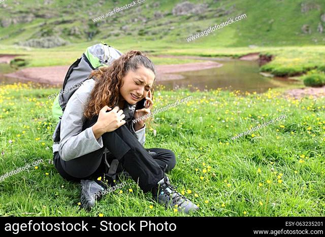 Injured hiker complaining on the grass asking for help on phone