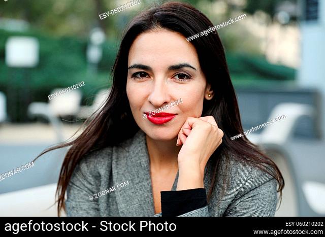 Portrait of business woman smiling outdoor, wearing grey suit. High quality photo