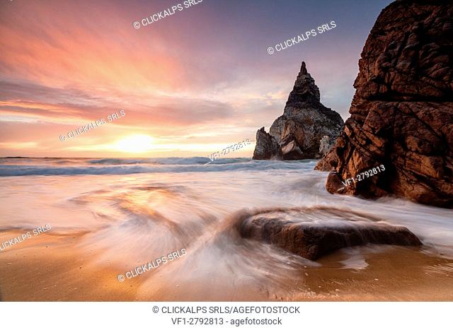 Golden reflections of the cliffs on Praia da Ursa beach bathed by ocean at sunset Cabo da Roca Colares Sintra Portugal Europe