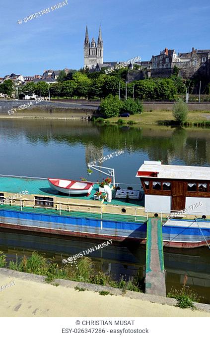 Closeup barge on the Maine river at Angers and the cathedral Saint Maurice at the top of hill in the background. Angers is a commune in the Maine-et-Loire...