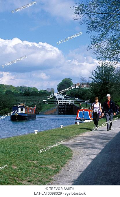 Kennet & Avon canal. Caen Hill staircase, series of locks. Canal narrow boat. Couple on tow path