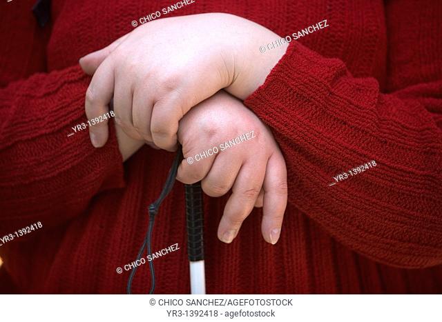 The hands of a blind female student hold her cane