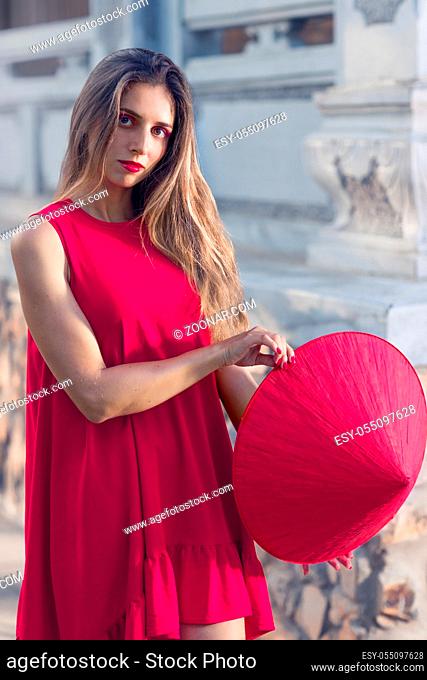 Fashion portrait of a beautiful woman in red conical hat outdoor