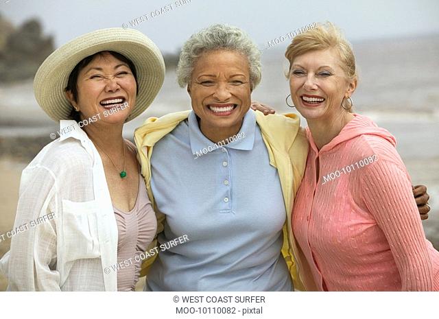 Three female friends embracing at beach portrait