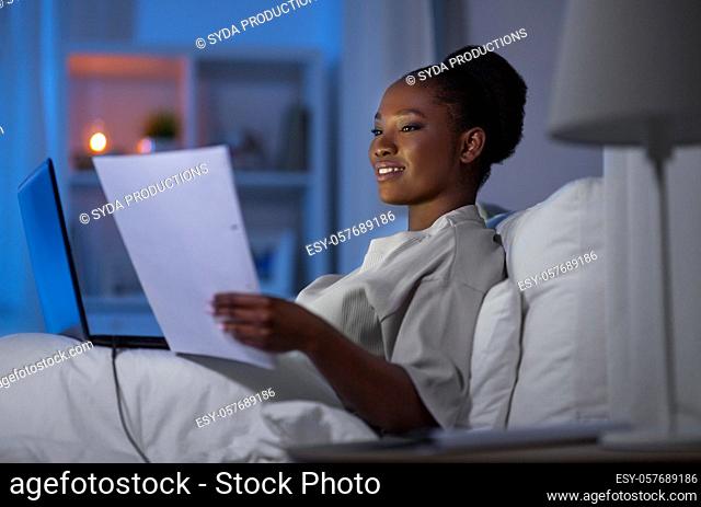 woman with laptop working in bed at night