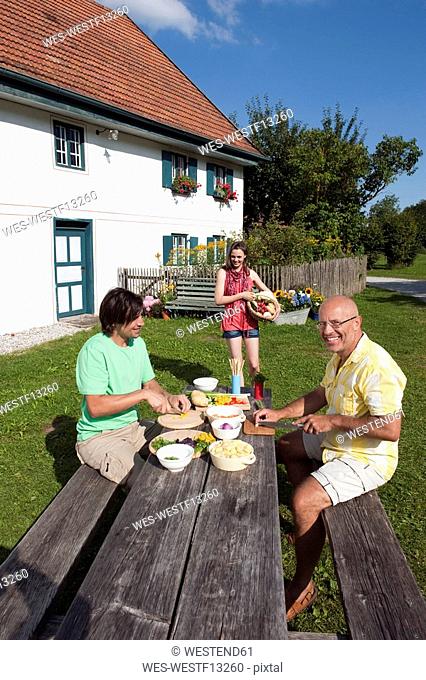 Germany, Bavaria, Two men at table in garden preparing food