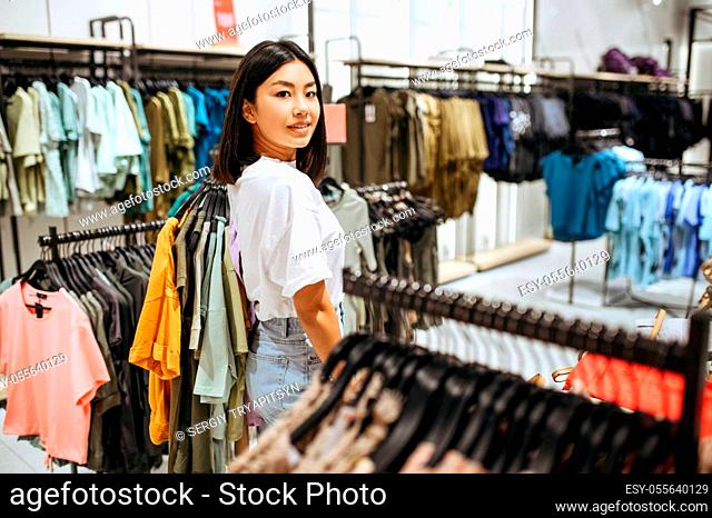Woman choosing clothes in clothing store. Female person shopping in fashion boutique, shopaholic, shopper looking on garment