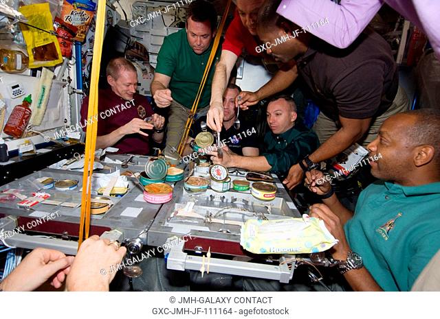 Expedition 21 and STS-129 crew members gather for a meal at the galley in the Unity node of the International Space Station while space shuttle Atlantis remains...