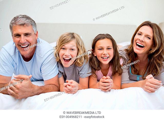Laughing family lying on the bed