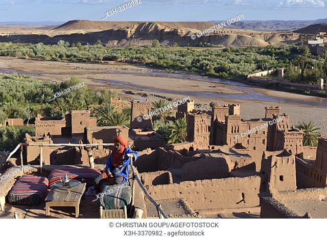 man sitting on the terrace of a cafe overlooking the Ksar of Ait-Ben-Haddou, Ounila River valley, Ouarzazate Province, region of Draa-Tafilalet, Morocco