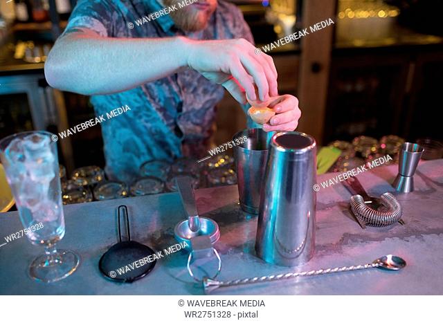 Bartender adding egg yolk while preparing drink at counter