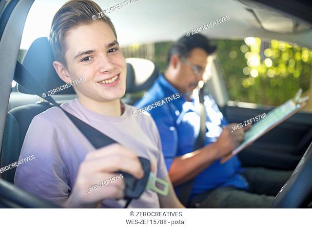 Portrait of smiling learner driver with instructor in car