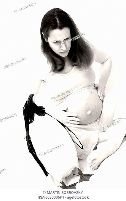 pregnant woman holding her belly / penguin in foreground