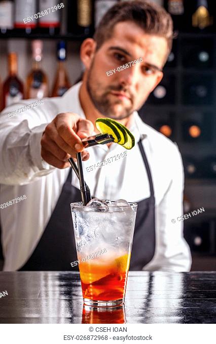 Barman decorating cocktail with lime