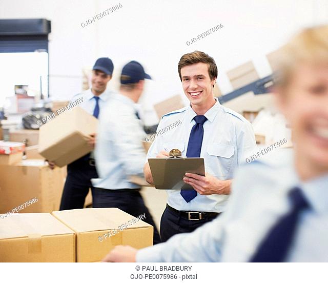 Worker writing on clipboard in shipping area