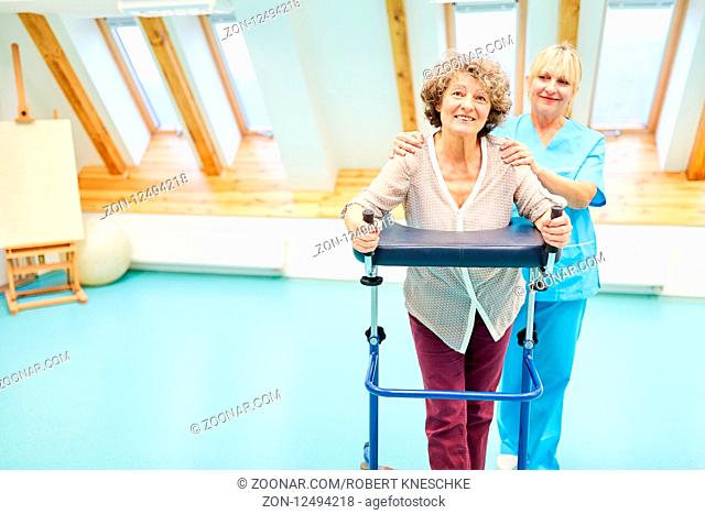 Seniorin als Patient lernt Gehen mit dem Rollator mit Unterstützung in der Reha