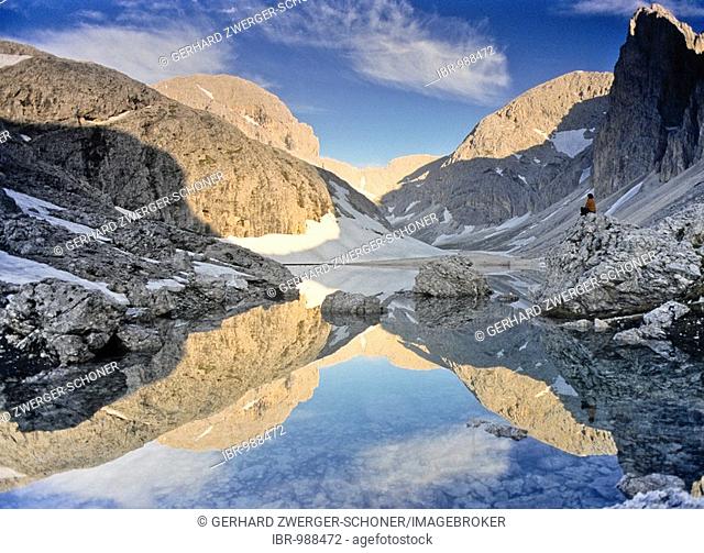 Hiker sitting by the Lago di Antermoia mountain lake, Rosengarten, South Tirol, Italy, Europe