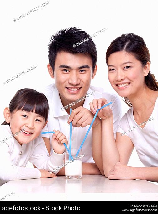 Family sharing a glass of milk, studio shot