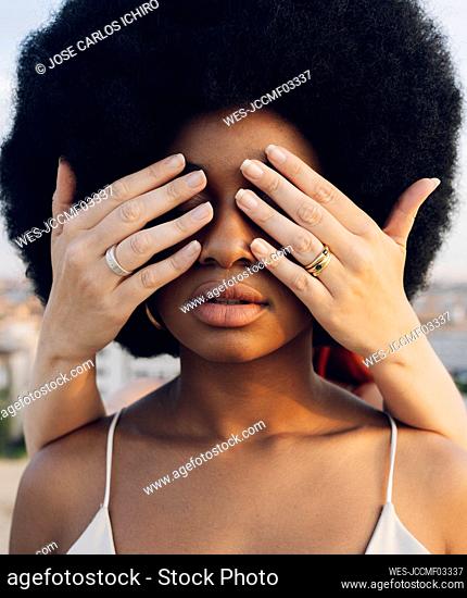Young woman covering Afro girlfriend's eyes