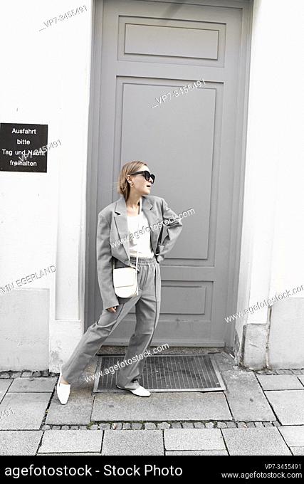 Fashionable woman in gray suit, standing in front of door. Munich, Germany