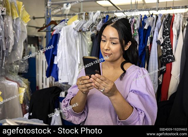 Woman using phone while working at dry cleaners
