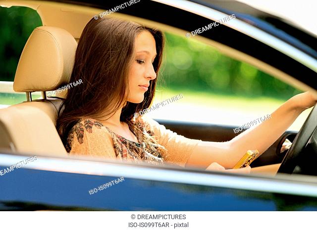 Girl sitting in drivers seat of car using cell phone