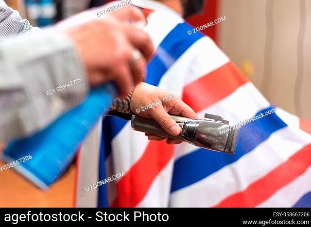 Barber cleaning electric hair clipper at barber shop