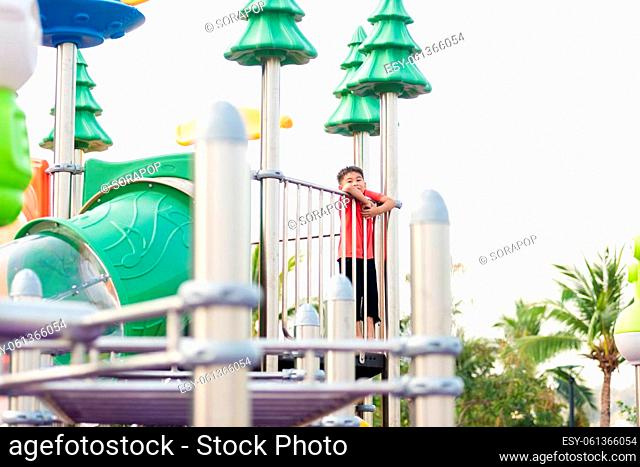 Asian child playing on outdoor playground, happy preschool little kid having funny while playing on the playground equipment in the daytime in summer