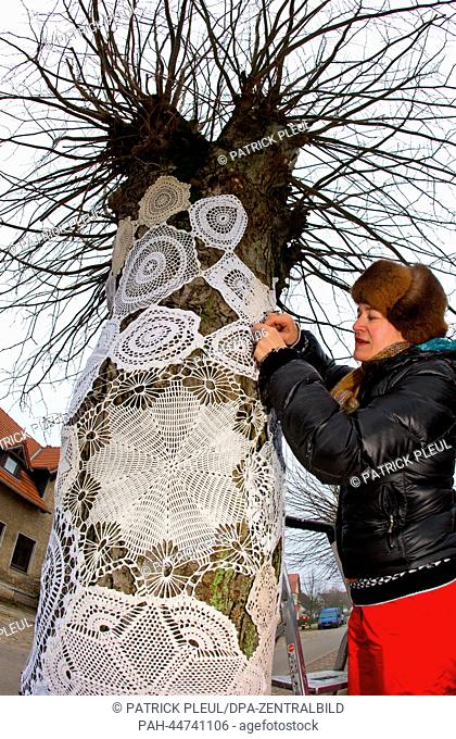 Chairwoman of the Pirate Party in Brandenburg Anke Domscheit-Berg wraps the trunk of a tree with an embroidered covering outside of the Christmas post office...