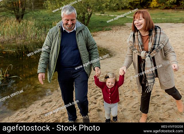 Grandparents walking on sand with granddaughter